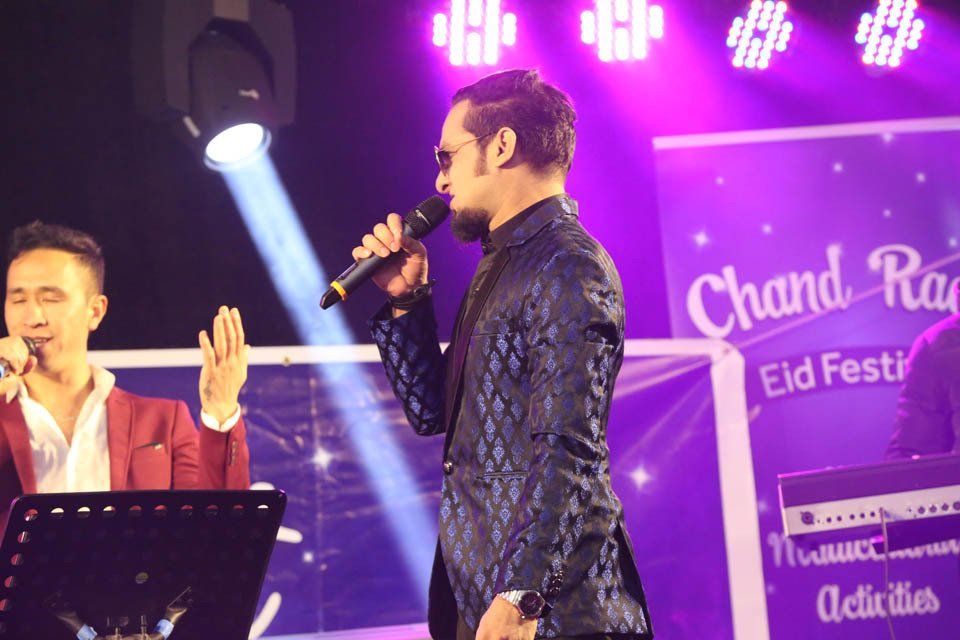 A man singing into a microphone while another man plays a keyboard