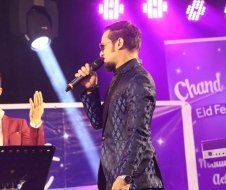 A man in a suit is singing into a microphone on a stage.