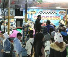 A group of people are standing in front of a sign that says gems.