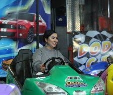 A woman is sitting in a green bumper car.