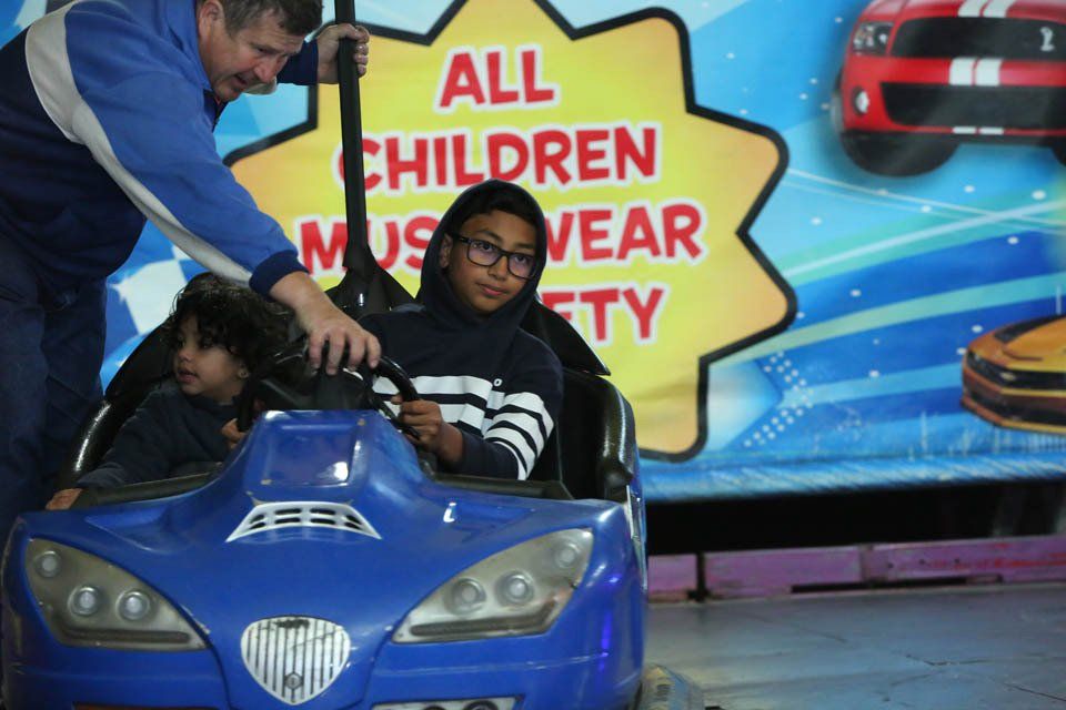 A man is helping a young boy in a blue toy car