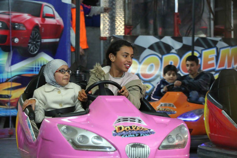 A woman and two children are riding a pink bumper car