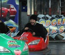 A man in a black hat is riding a bumper car at an amusement park