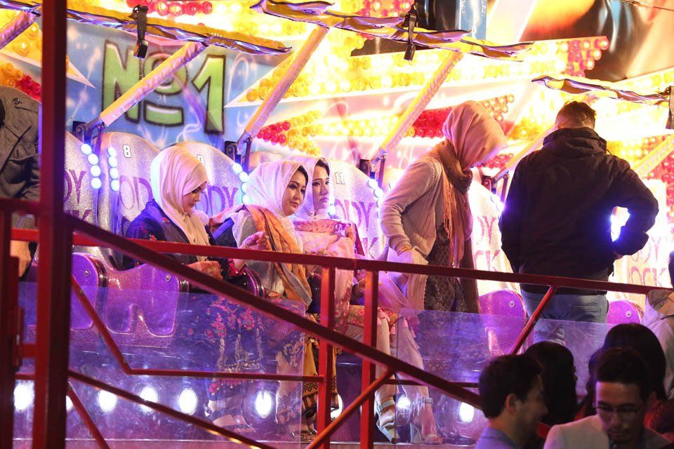 A group of people are riding a roller coaster at a carnival.
