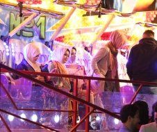 A group of people are standing in front of a carnival ride.