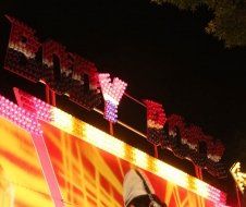 A person is riding a roller coaster at a carnival at night.