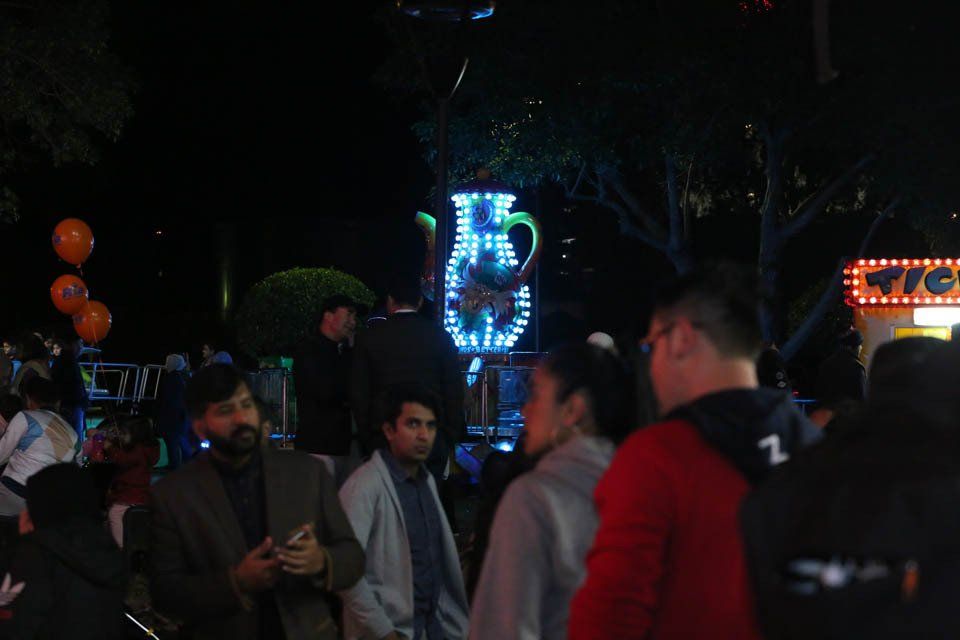 A group of people are standing in a dark park at night.