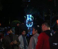 A group of people are standing in a dark room talking to each other.