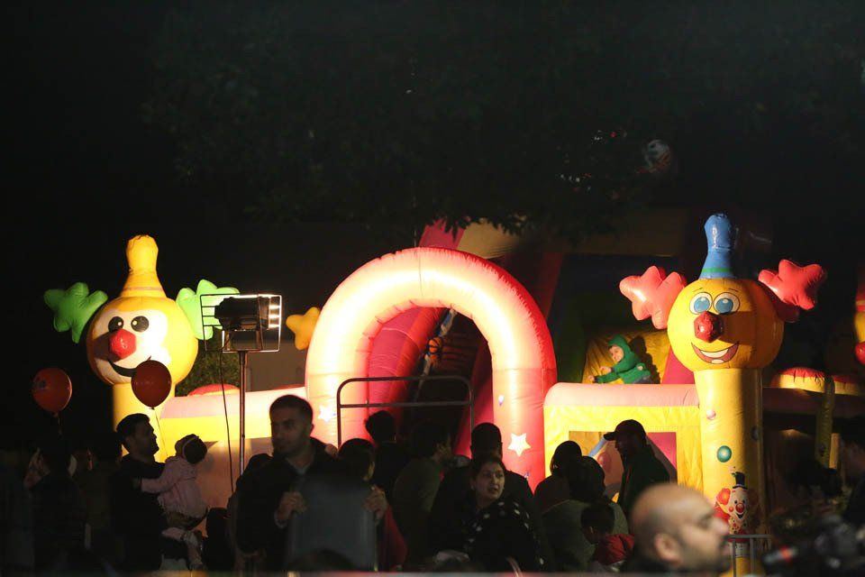 A group of people are gathered around a bouncy house with clown faces on it