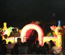 A group of people are standing around a bouncy house at night