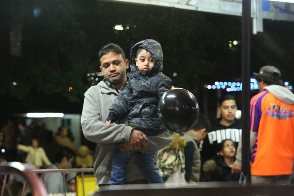 A man is holding a child in his arms while holding a black balloon.