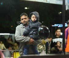 A man is holding a little boy who is holding a bowling ball.
