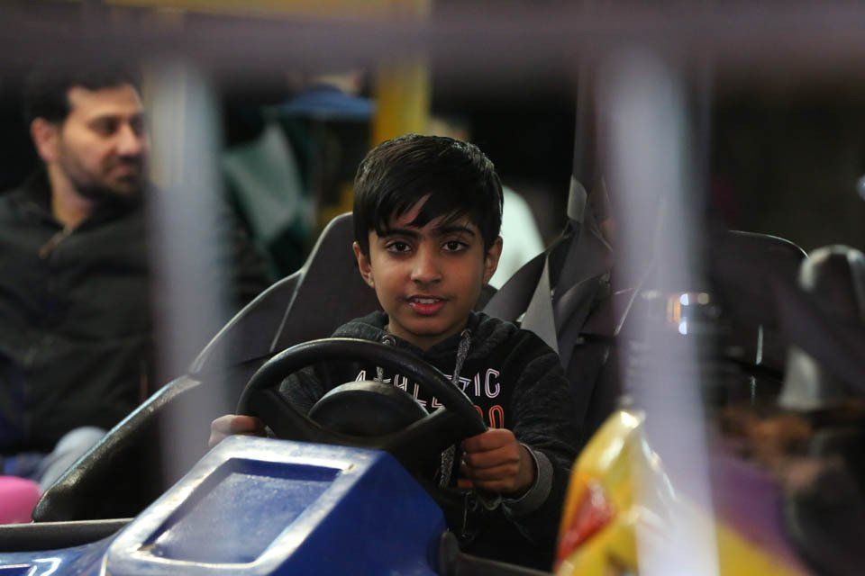 A young boy is driving a go kart in an amusement park.