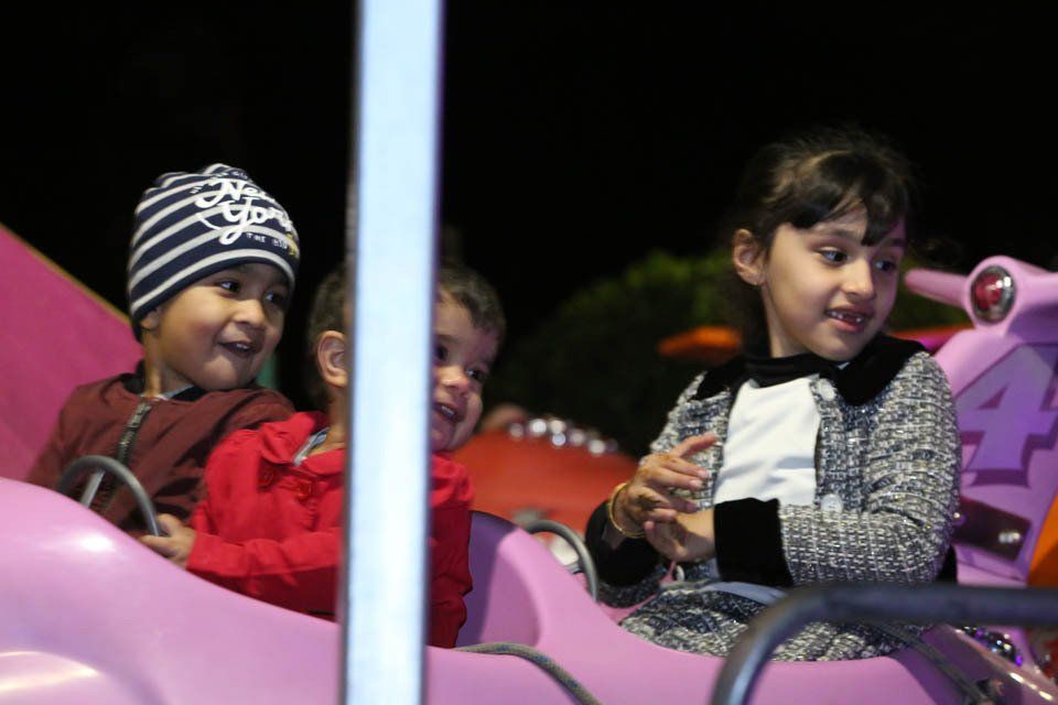 Three children are riding a pink car with the number 4 on it