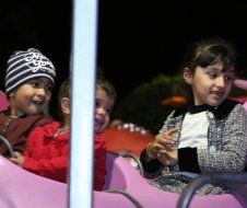 A group of children are riding a roller coaster at night.