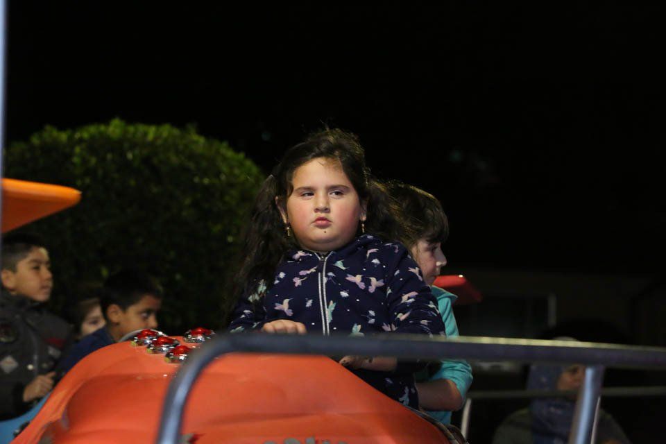 A little girl is riding a roller coaster at night.