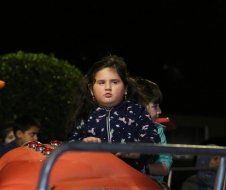 A little girl is riding a roller coaster at night.