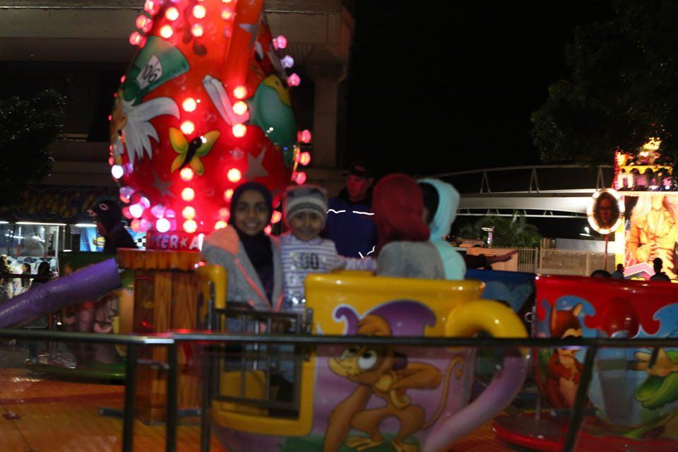A group of people are riding a teacup ride at night