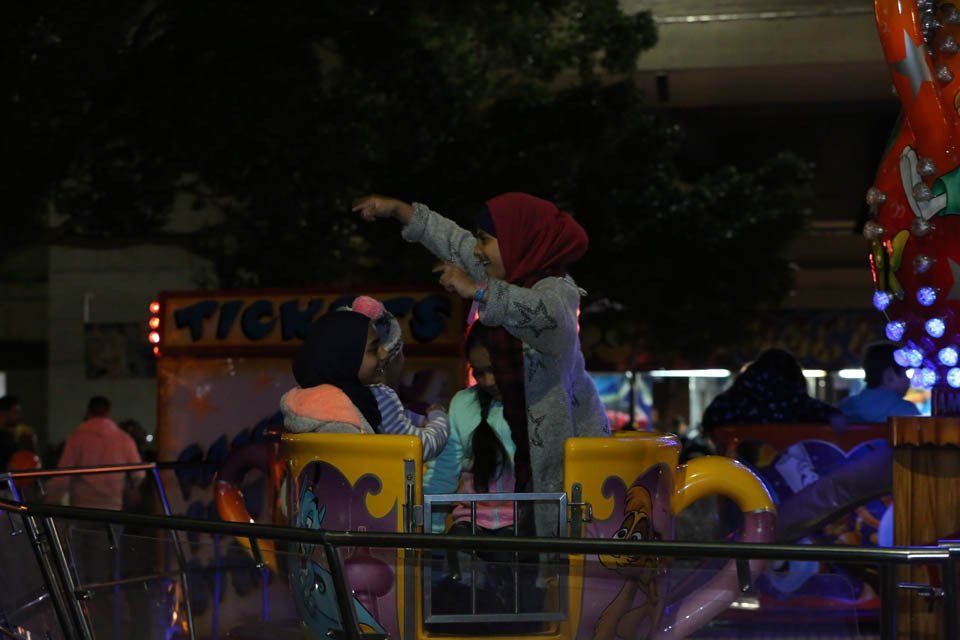A group of people are riding a roller coaster at night.