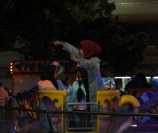 A group of people are riding a roller coaster at night.