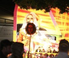 A woman is singing into a microphone in front of a large screen.