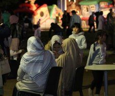 A group of people are sitting around a table in a park at night.