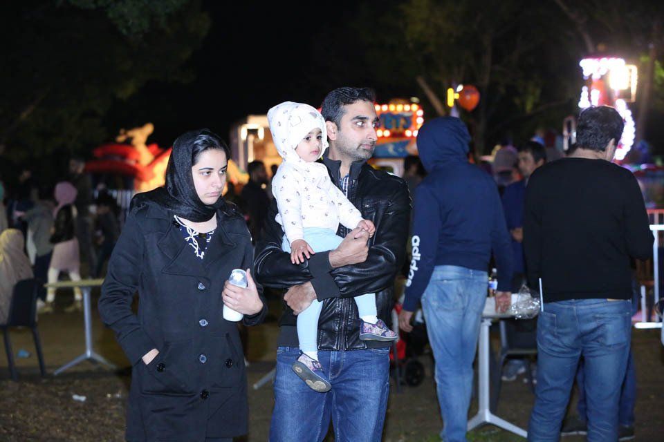 A man is holding a baby in his arms while a woman looks on.