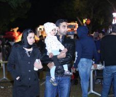 A man is holding a baby in his arms in a crowd of people.