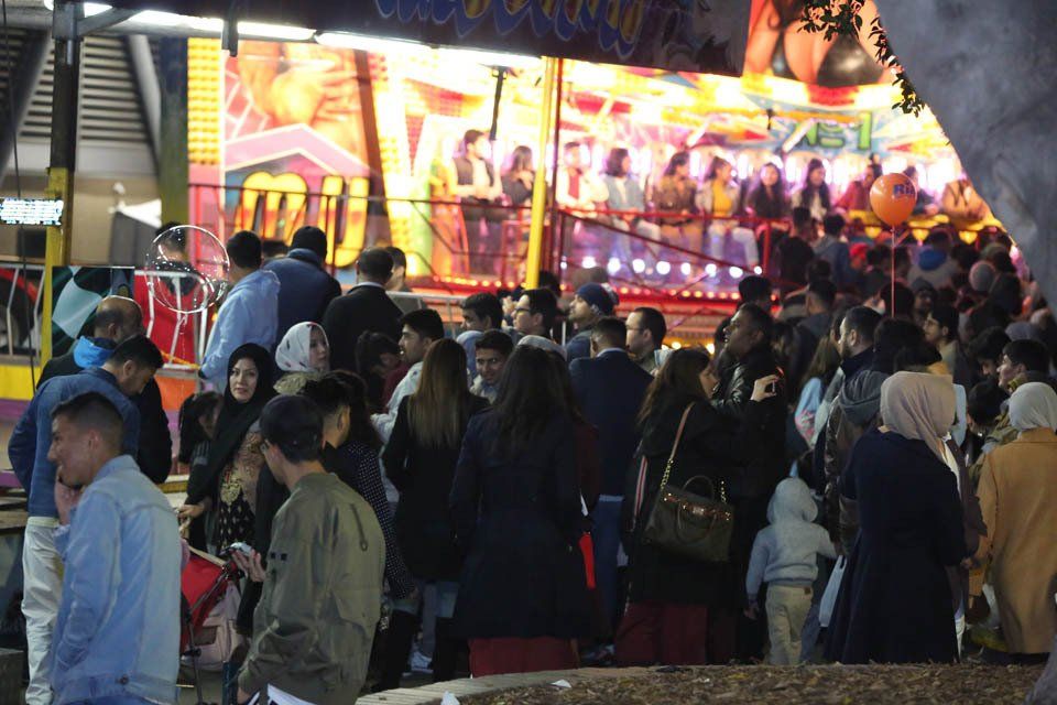 A crowd of people are gathered in front of a carnival ride