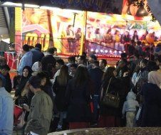 A large group of people are standing in front of a carnival ride.