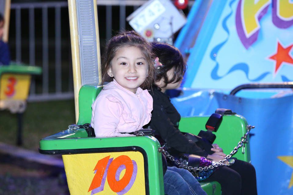 A little girl is riding a ride with the number 10 on it
