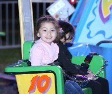 A little girl is sitting in a green chair with the number 10 on it.