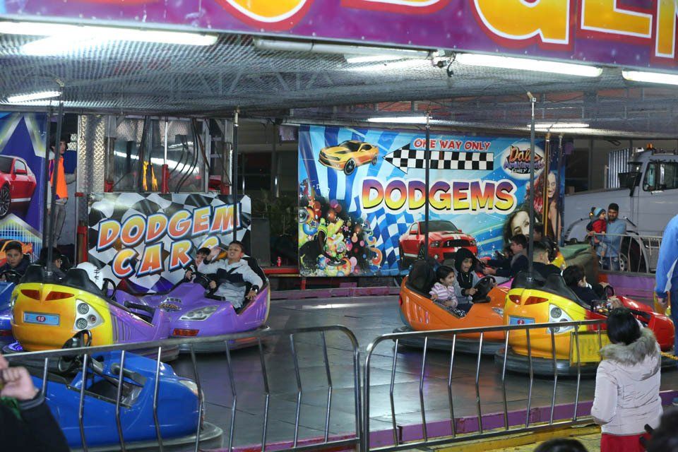 A group of people are riding bumper cars in front of a sign that says dodgems