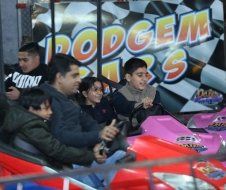 A group of people are riding go karts in front of a sign that says dodge 's