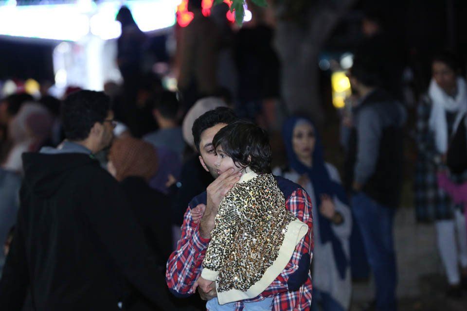 A man is holding a baby in his arms in a crowd of people.