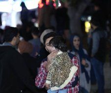 A man is holding a baby in his arms in a crowd of people.