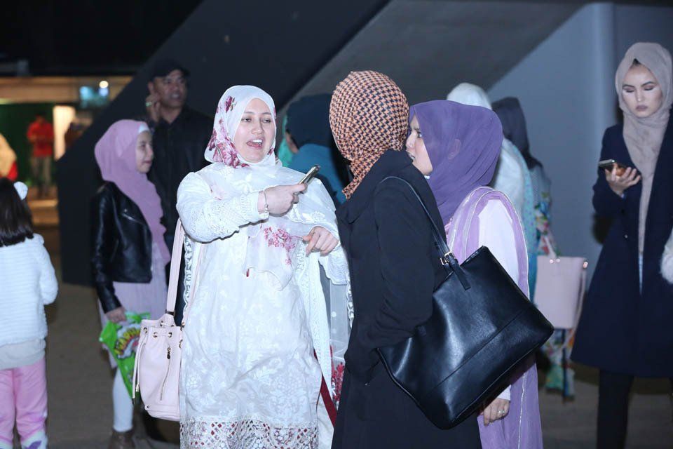 A group of women are standing in a line talking to each other.