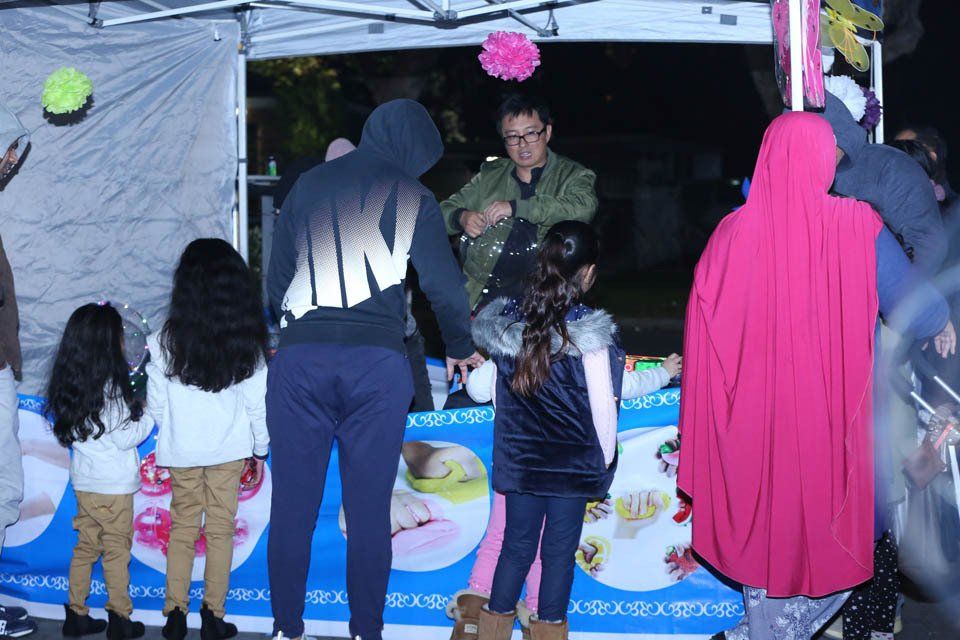 A group of people are standing in front of a food stand.