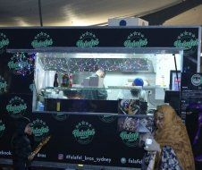A woman is standing in front of a food truck.