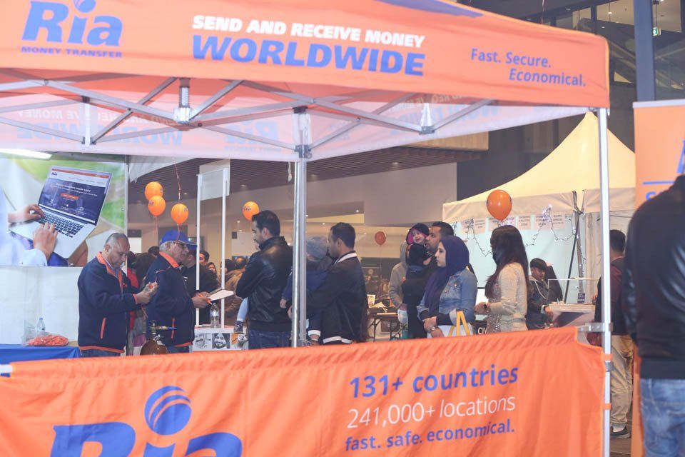 A group of people standing under a tent that says ria worldwide