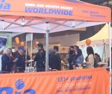 A group of people standing under a tent that says send and receive money worldwide