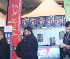 A group of men are standing in front of a sign that says jadootv