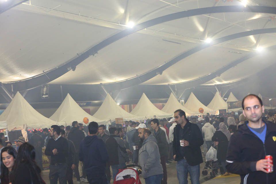 A crowd of people are gathered under a tent at night