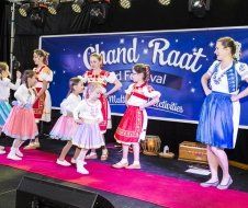 A group of young girls are dancing on a stage at a festival.