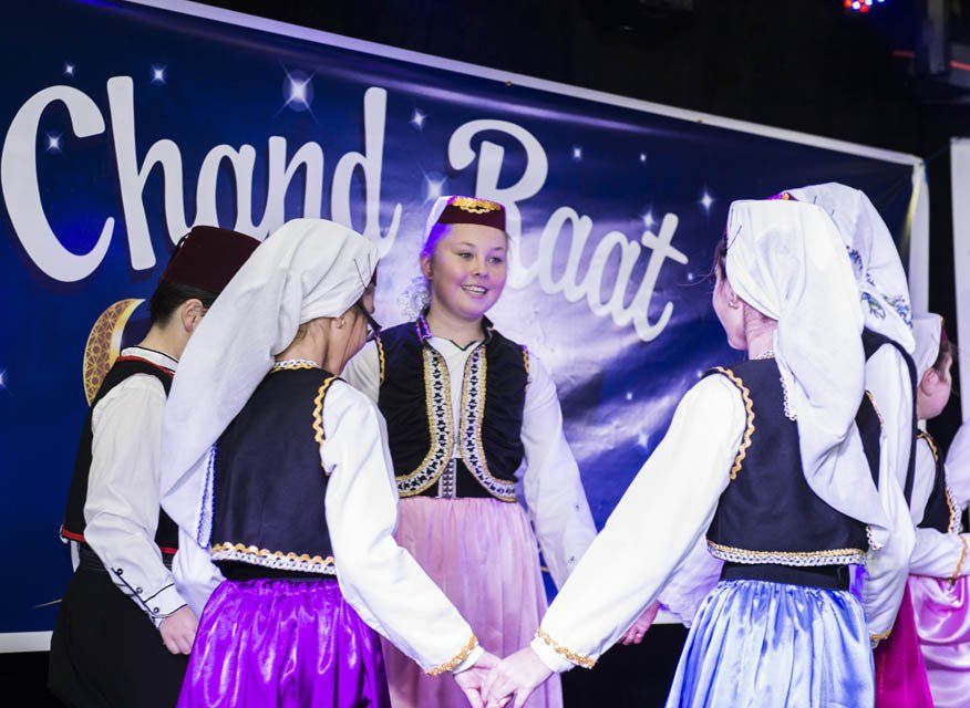 A group of people are dancing in front of a sign that says chand raat