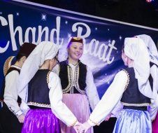 A group of women are dancing in front of a sign that says chand raat.