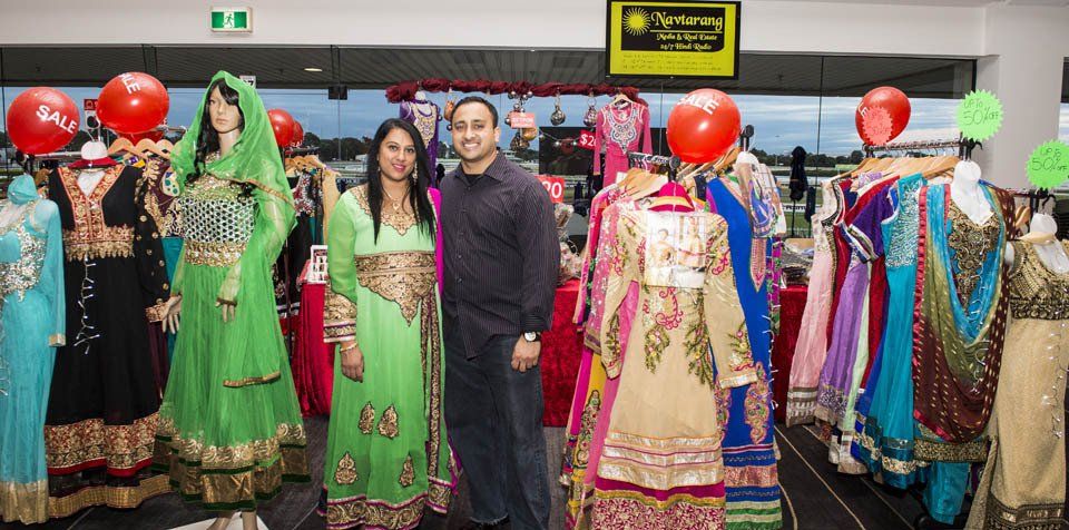 A man and a woman are standing in front of a display of dresses in a store.