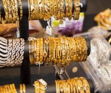 A bunch of gold bracelets are displayed on a stand.