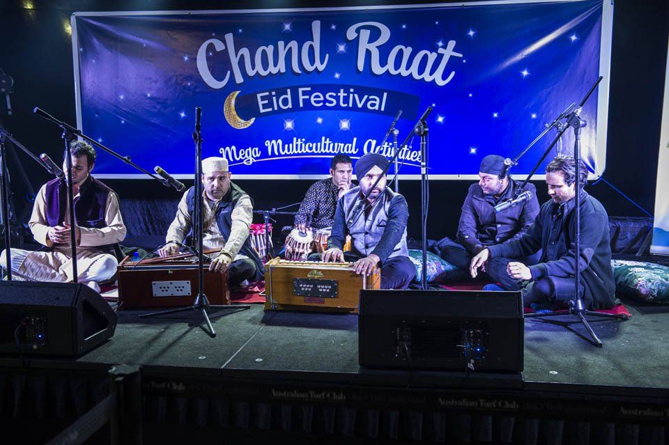 A group of men are sitting on a stage playing instruments.