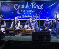 A group of men are sitting on a stage playing instruments.